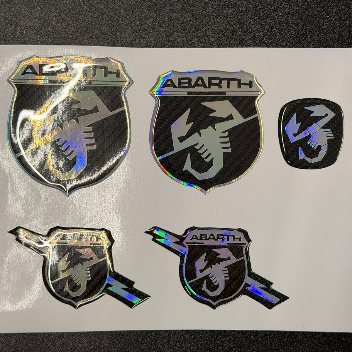 Set 5 copriloghi resinati carbonio per Abarth: laterali, frontale, posteriore e volante